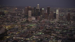 AX69_078 - 4.8K aerial stock footage tilt from urban streets and apartments to reveal and approach the Downtown Los Angeles skyline at night, California