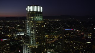 AX69_116 - 4.8K aerial stock footage of orbiting the top of US Bank Tower in Downtown Los Angeles at night, California