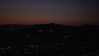 AX69_135 - 4.8K aerial stock footage of radio tower and the lights of homes atop the Hollywood Hills at night, California