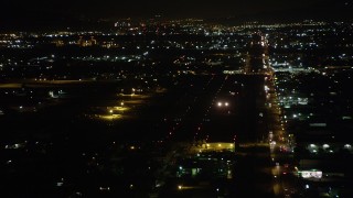 AX69_158 - 4.8K aerial stock footage of small airplane landing at Whiteman Airport at night in Pacoima, California