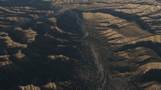 AX70_022 - 4K aerial stock footage Dry riverbed between mountain ridges in Los Padres National Forest at sunrise, California