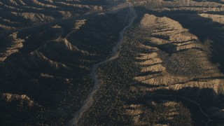 AX70_023 - 4K aerial stock footage of A view of a dry riverbed between mountain ridges in Los Padres National Forest at sunrise, California