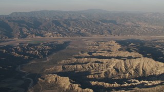 AX70_029 - 4K aerial stock footage Dry riverbed and mountain ridges near farms at sunrise, Cuyama, California