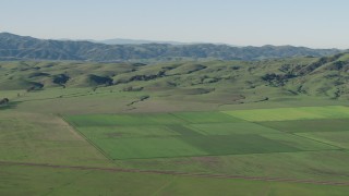 AX70_109 - 4K aerial stock footage Flyby farm fields beside green hills in Hollister, California