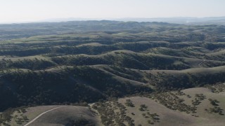 AX70_176 - 4K aerial stock footage Flying over green hills crossed by dirt roads in San Benito County, California