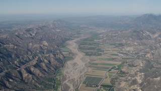 AX70_183 - 4K aerial stock footage Farm fields and Santa Clara River bordered by mountains in Piru, California