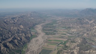 AX70_184 - 4K aerial stock footage Farm fields and Santa Clara River surrounded by mountains in Piru, California