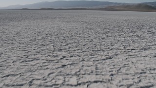 AX70_216 - 4K aerial stock footage Fly low over Soda Lake in California, and tilt to reveal desert mountains