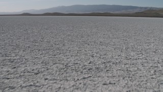 AX70_219 - 4K aerial stock footage Tilt from a close-up of the surface of Soda Lake in California, and reveal desert mountain range