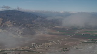 AX70_245 - 4K aerial stock footage Fly through a cloud to reveal farm fields in Greenfield, California