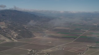 AX70_246 - 4K aerial stock footage Fly through a misty cloud and tilt to farm fields in Greenfield, California