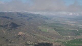 AX70_264 - 4K aerial stock footage of cloud-capped Santa Lucia Range mountain slopes and farmland in Soledad, California