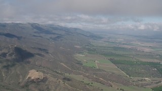 AX70_265 - 4K aerial stock footage of flying over Santa Lucia Range mountain slopes beside farmland in Soledad, California