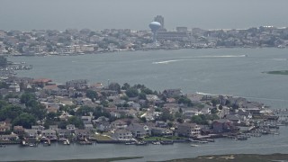 AX71_160E - 5.1K aerial stock footage of boats on a bay by coastal neighborhoods in Brigantine, New Jersey