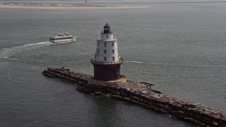 AX72_025 - 5.1K aerial stock footage orbiting Harbor of Refuge Light, Delaware and reveal a passing ferry