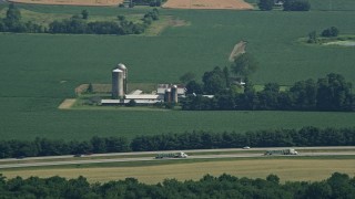AX72_112 - 5.1K aerial stock footage of a farm with silos and barns near the highway in Centreville, Maryland