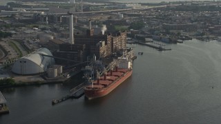 AX73_101 - 5.1K aerial stock footage of a cargo ship docked by the Domino Sugar Factory, Baltimore, Maryland