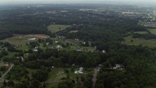 AX74_146E - 4.8K aerial stock footage flying over forest to approach rural homes in Manassas, Virginia