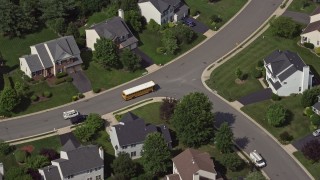AX75_004 - 4.8K aerial stock footage tracking a school bus in a suburban neighborhood in Manassas, Virginia