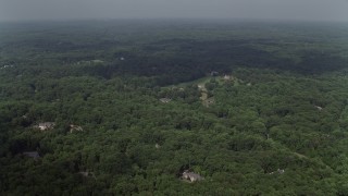 AX75_008E - 4.8K aerial stock footage flying over forest, approaching upscale homes, Clifton, Virginia