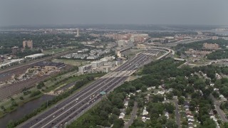 AX75_033E - 4.8K aerial stock footage flying by Interstate 95 between train yard and suburban homes in Alexandria, Virginia