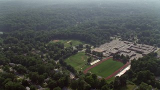 AX75_145E - 4.8K stock footage aerial video flying over Stuart High School beside Lake Barcroft in Falls Church, Virginia