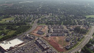 AX75_171E - 4.8K aerial stock footage flying over homes and streets to approach strip mall and stores in Manassas, Virginia