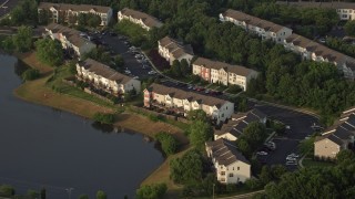 AX76_002 - 4.8K aerial stock footage flying by waterfront town houses beside pond, Manassas, Virginia, sunset