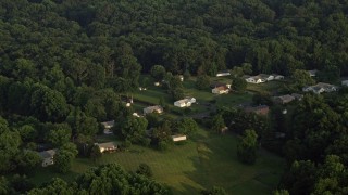 AX76_007E - 4.8K aerial stock footage flying by rural homes near forest, Manassas, Virginia, sunset