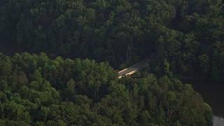 AX76_009 - 4.8K aerial stock footage flying by Yates Ford Road bridge, partially hidden in forest, Clifton, Virginia, sunset