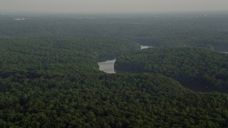 AX76_010 - 4.8K aerial stock footage flying by Occoquan River winding through forest, Clifton, Virginia, sunset