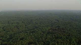 AX76_013 - 4.8K aerial stock footage flying by forest, partially hidden rural homes, Clifton, Virginia, sunset