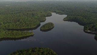 AX76_015 - 4.8K aerial stock footage flying by Burke Lake, tree-covered shores, Fairfax Station, Virginia, sunset