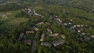 AX76_017E - 4.8K stock footage aerial video flying over town houses, power lines, trees, and row houses in Springfield, Virginia, sunset