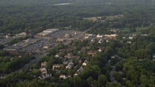 AX76_019E - 4.8K aerial stock footage flying by town houses near strip malls, Springfield, Virginia, sunset