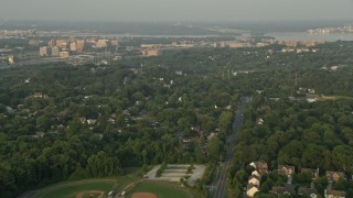 AX76_026E - 4.8K aerial stock footage flying over baseball fields, suburban neighborhoods, Alexandria, Virginia, sunset