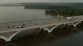 AX76_033 - 4.8K aerial stock footage of cars crossing Woodrow Wilson Memorial Bridge, Potomac River, Fort Washington, Maryland, sunset