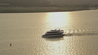 AX76_039 - 4.8K aerial stock footage tracking a ferry on the Potomac River Arlington, Virginia, sunset