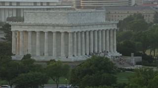 AX76_067E - 4.8K stock footage aerial video flying by Lincoln Memorial with tourists on the steps, Washington D.C., sunset