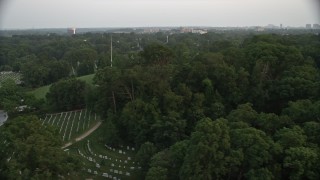 AX76_116 - 4.8K aerial stock footage of gravestones and trees at Arlington National Cemetery, Virginia, twilight