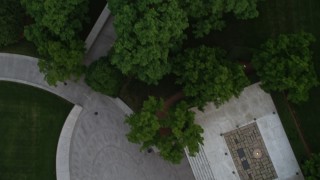 AX76_117 - 4.8K stock footage aerial video flying over Arlington National Cemetery trees to reveal President John F. Kennedy Gravesite, Virginia, twilight