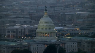 AX76_168E - 4.8K aerial stock footage of the United States Capitol dome, office buildings in background, Washington, D.C., twilight