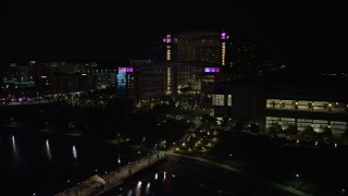 AX77_014 - 4.8K aerial stock footage flying by pier and Gaylord National Resort & Convention Center, National Harbor, Maryland, night
