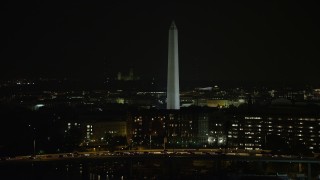 AX77_039 - 4.8K aerial stock footage approaching a bridge, office buildings, and Washington Monument, Washington, D.C., night