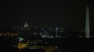 AX77_052 - 4.8K aerial stock footage of the United States Capitol dome, construction cranes, and the Washington Monument, Washington, D.C., night