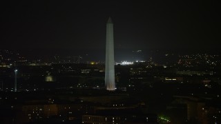 AX77_060E - 4.8K aerial stock footage of Washington Monument circled by American flags, Washington, D.C., night