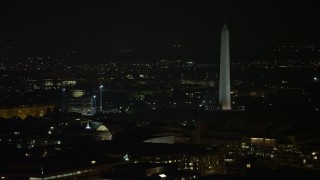 AX77_063 - 4.8K aerial stock footage of Washington Monument ringed by flags in Washington, D.C., night