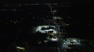 AX77_074E - 4.8K aerial stock footage following Columbia Pike to approach a car dealership and shops in Arlington, Virginia, night