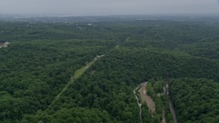 AX78_075 - 4.8K aerial stock footage of a row of power lines through forest by Ellicott City, Maryland