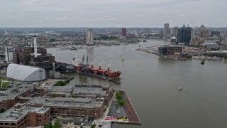 AX78_105 - 4.8K aerial stock footage approaching Domino Sugar Factory and cargo ship beside Patapsco River, Maryland